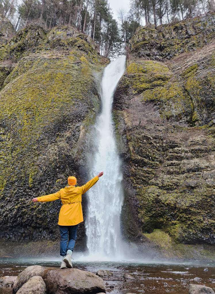 Dancing under Hoerseshoe Falls Oregon in yellow rain jacket